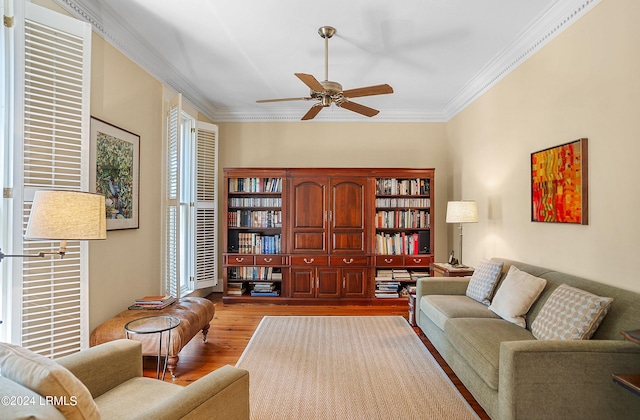 sitting room featuring light wood-style floors, crown molding, and a ceiling fan