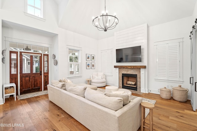 living room with a stone fireplace, hardwood / wood-style floors, and an inviting chandelier