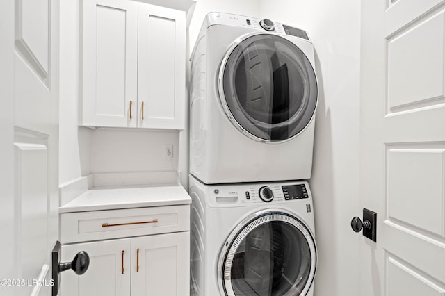 clothes washing area featuring cabinets and stacked washer and clothes dryer