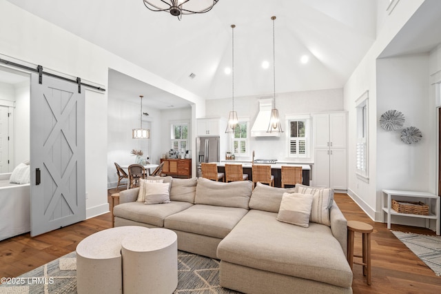 living room featuring a barn door, hardwood / wood-style floors, and high vaulted ceiling