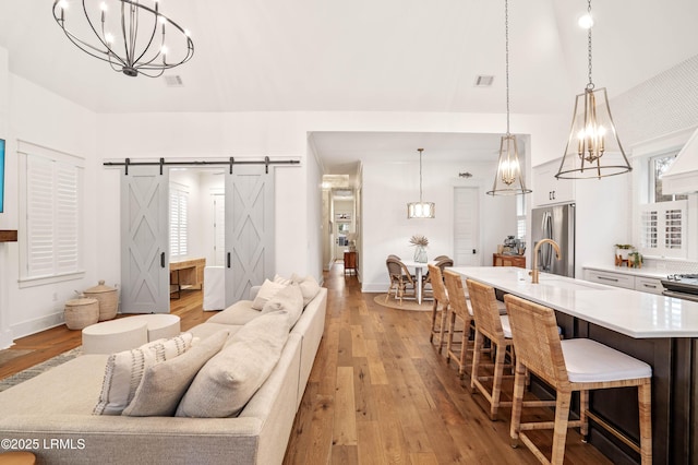 living room with sink, light hardwood / wood-style flooring, and a barn door