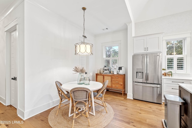 dining area featuring ornamental molding, light hardwood / wood-style flooring, and a wealth of natural light