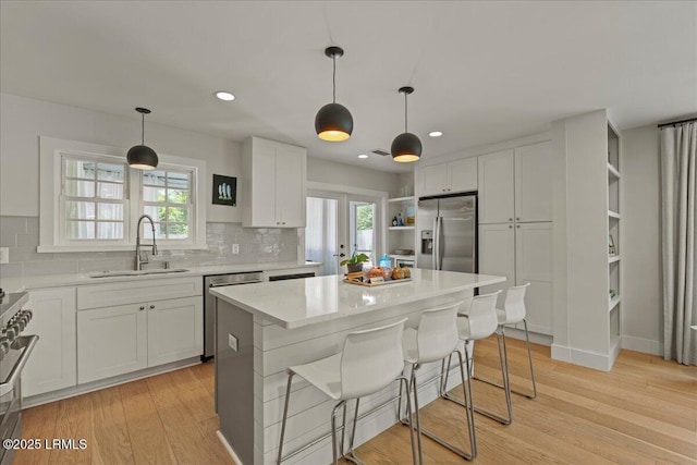 602 Huguenin Dr, Beaufort, SC 29902 - kitchen featuring stainless steel appliances, tasteful backsplash, white cabinetry, light wood-style floors, and a kitchen island