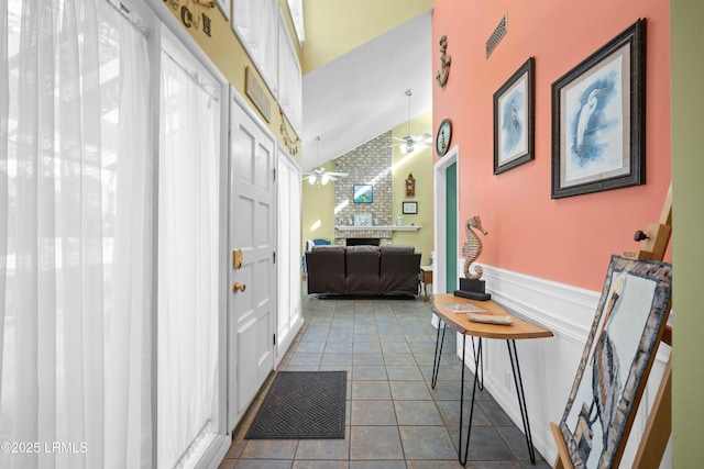 hallway with lofted ceiling, a wainscoted wall, and tile patterned floors