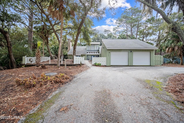 view of front of property featuring board and batten siding, an attached garage, fence private yard, and aphalt driveway