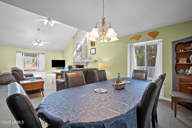 tiled dining room with vaulted ceiling, a brick fireplace, and ceiling fan with notable chandelier