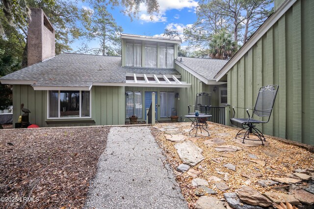 back of property featuring a patio area, roof with shingles, and a chimney