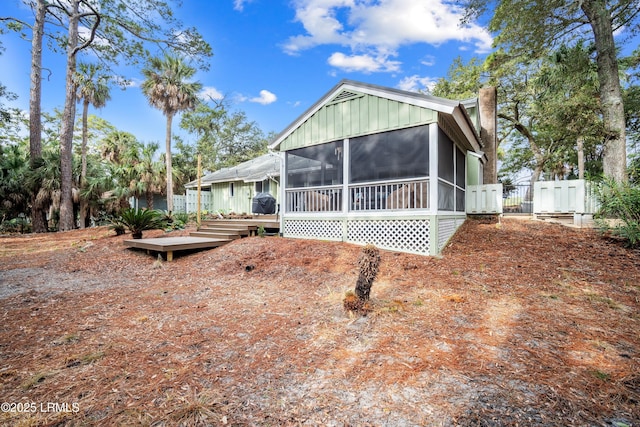 exterior space featuring a gate, a chimney, fence, a wooden deck, and a sunroom