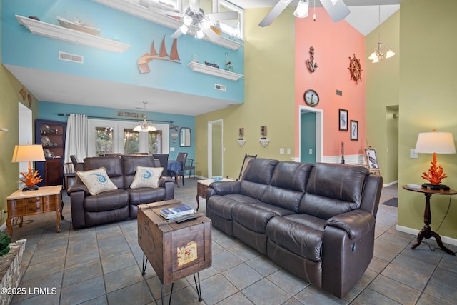 living room with baseboards, a towering ceiling, visible vents, and ceiling fan with notable chandelier