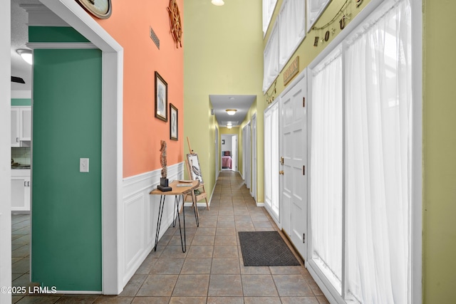 hall with tile patterned flooring and a towering ceiling