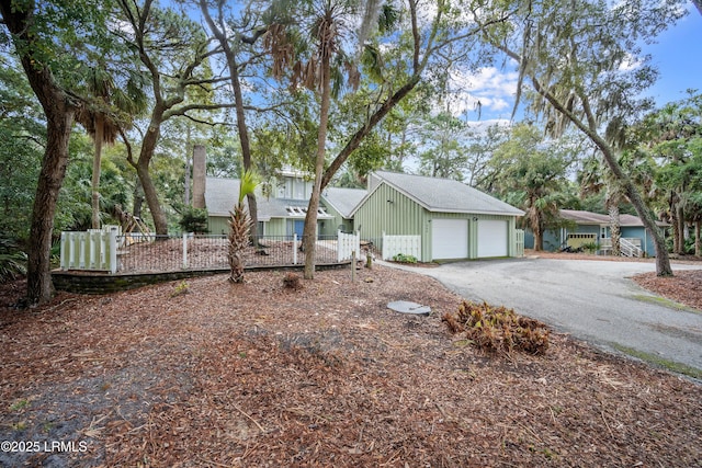 view of front of house featuring fence, aphalt driveway, and a garage