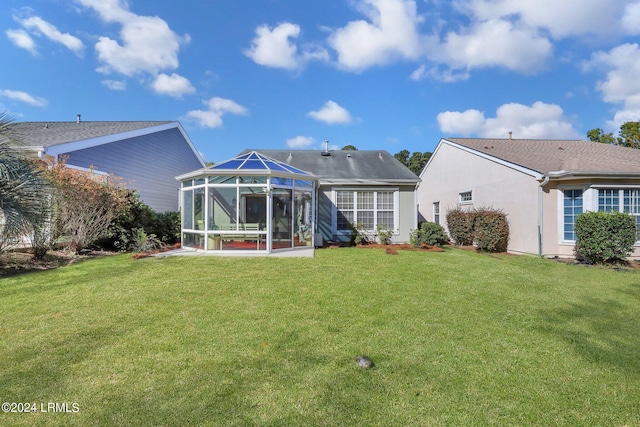 back of house with glass enclosure and a lawn