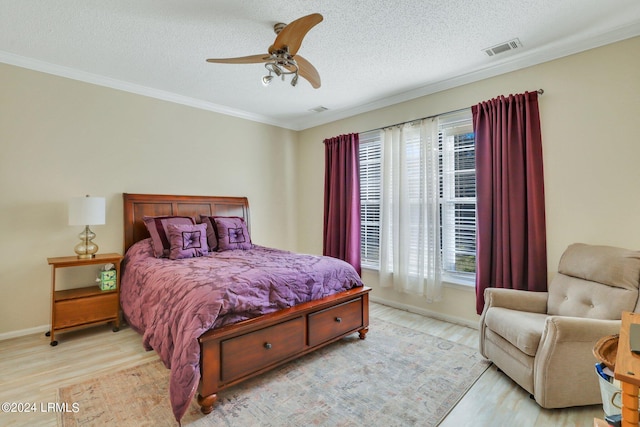 bedroom with a textured ceiling, ornamental molding, ceiling fan, and light wood-type flooring