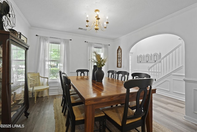 249 Hitching Post Cres, Bluffton, SC 29910 - dining space featuring a chandelier, wood finished floors, arched walkways, crown molding, and wainscoting