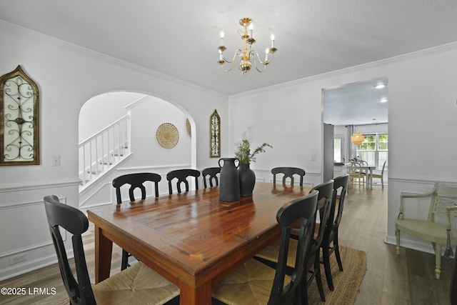 249 Hitching Post Cres, Bluffton, SC 29910 - dining room featuring ornamental molding, stairway, a chandelier, a wainscoted wall, and arched walkways