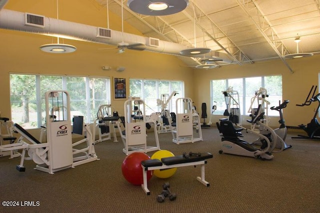 workout area with ceiling fan and high vaulted ceiling