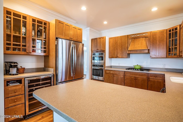 kitchen with wine cooler, sink, ornamental molding, appliances with stainless steel finishes, and custom range hood