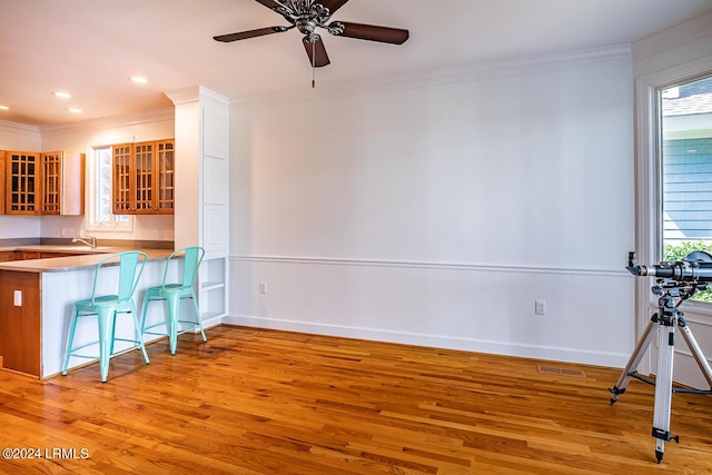 kitchen featuring crown molding, a breakfast bar, sink, and light hardwood / wood-style flooring