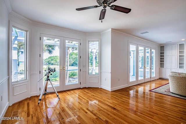 doorway with crown molding, built in shelves, light hardwood / wood-style floors, and french doors