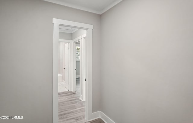 corridor with ornamental molding and light hardwood / wood-style floors