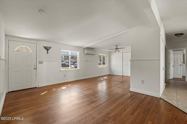 unfurnished living room featuring ceiling fan, dark hardwood / wood-style flooring, and a wall mounted AC