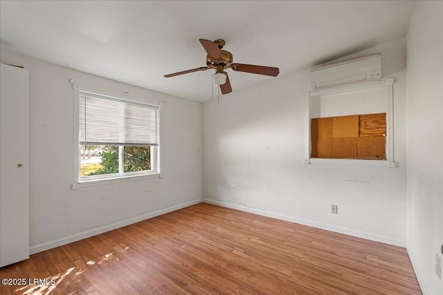 spare room featuring ceiling fan, a wall unit AC, and light hardwood / wood-style floors