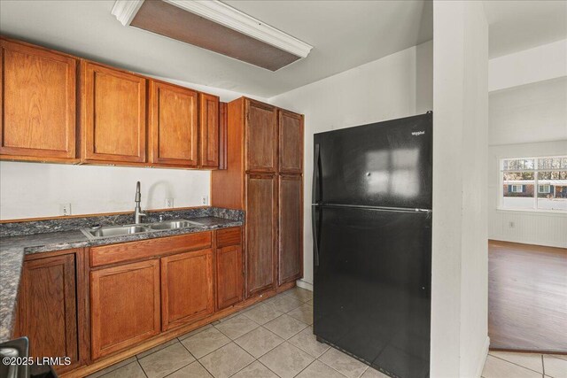 kitchen featuring black refrigerator, sink, and light tile patterned floors