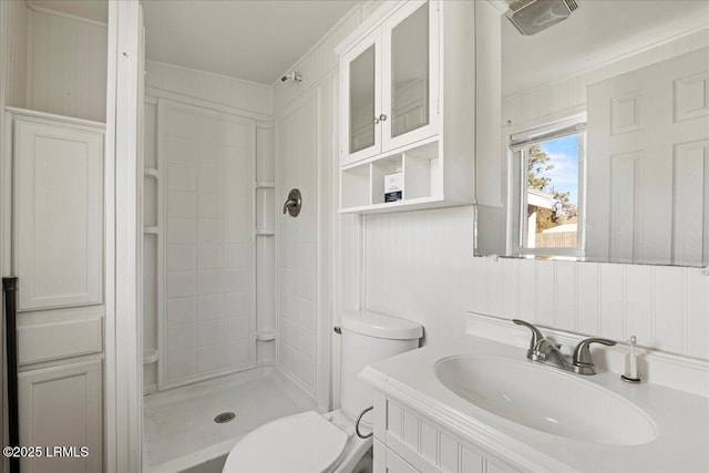 bathroom with tiled shower, vanity, and toilet