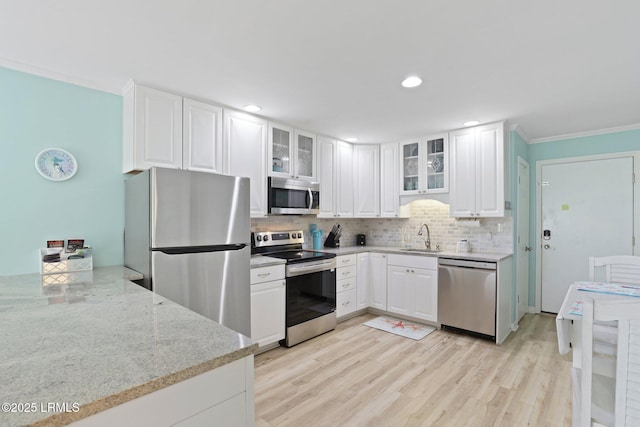 15 S Forest Beach Dr Unit 1D, Hilton Head Island, SC 29928 - kitchen featuring appliances with stainless steel finishes, ornamental molding, tasteful backsplash, white cabinets, and light stone countertops