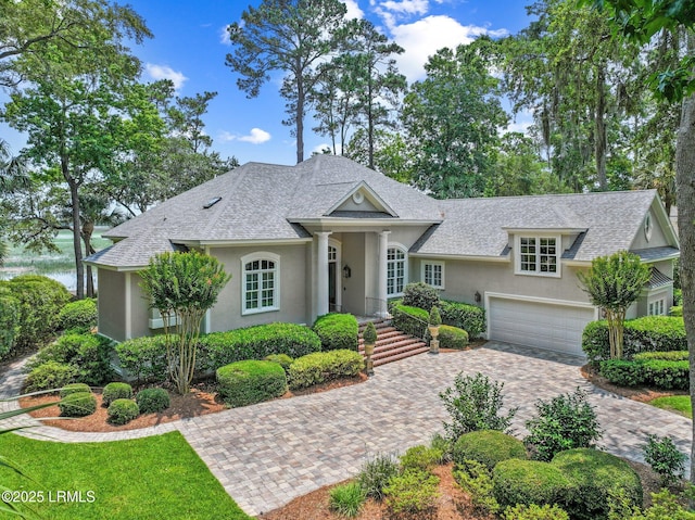 71 Peninsula Dr, Hilton Head Island, SC 29926 - view of front facade with stucco siding, decorative driveway, roof with shingles, and a garage