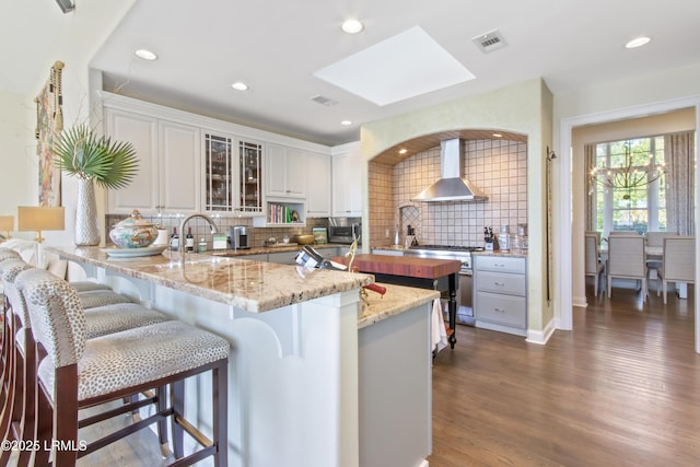 71 Peninsula Dr, Hilton Head Island, SC 29926 - kitchen featuring wall chimney exhaust hood, high end stainless steel range, a skylight, decorative backsplash, and glass insert cabinets