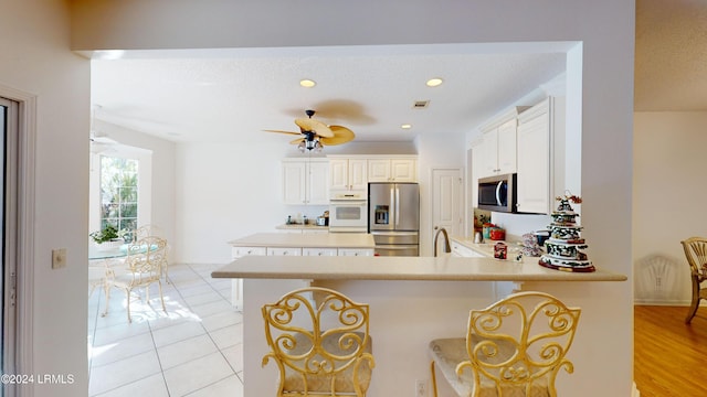 kitchen featuring white cabinetry, a kitchen breakfast bar, stainless steel appliances, and kitchen peninsula