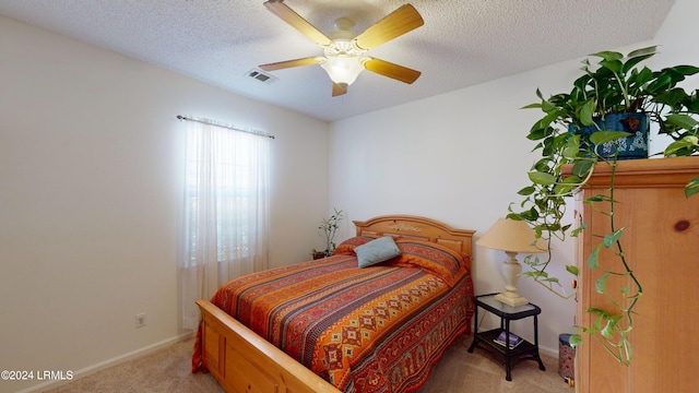 bedroom with ceiling fan, light carpet, and a textured ceiling