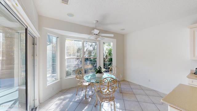 dining space featuring light tile patterned flooring, ceiling fan, lofted ceiling, and a textured ceiling