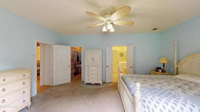 carpeted bedroom with a walk in closet, connected bathroom, ceiling fan, and a closet