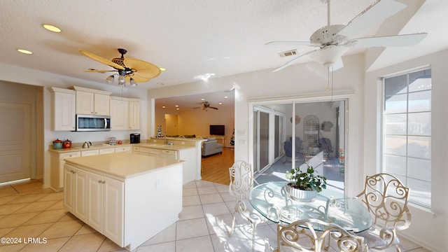 kitchen featuring light tile patterned floors, a textured ceiling, ceiling fan, and kitchen peninsula