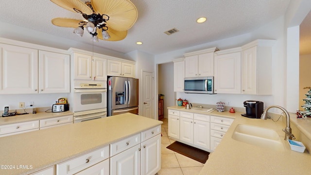 kitchen featuring stainless steel appliances, sink, light tile patterned floors, and white cabinets