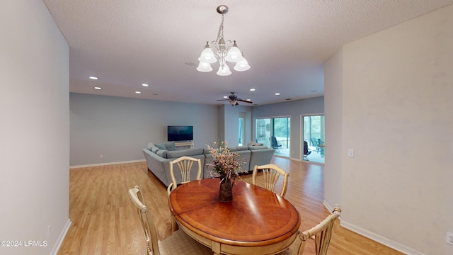 dining space featuring ceiling fan with notable chandelier, a textured ceiling, and light hardwood / wood-style floors