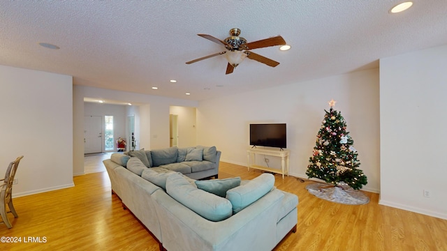 living room featuring ceiling fan, a textured ceiling, and light wood-type flooring