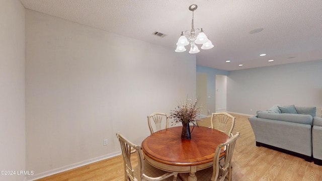 dining space with a notable chandelier, light hardwood / wood-style flooring, and a textured ceiling