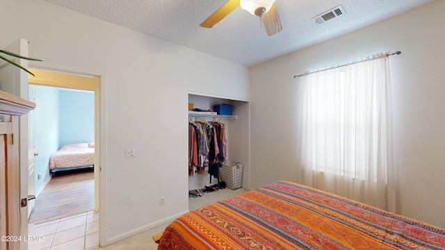 bedroom featuring multiple windows, a textured ceiling, a closet, and ceiling fan