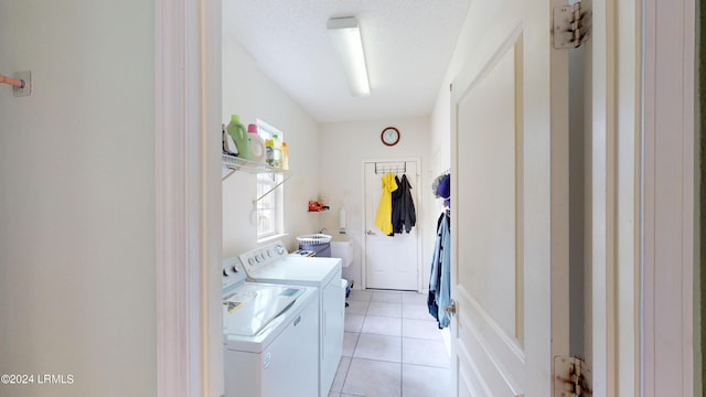 laundry room with washing machine and clothes dryer, a textured ceiling, and light tile patterned floors