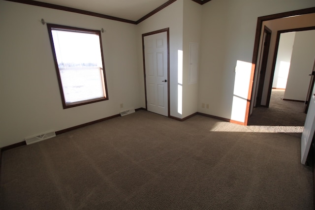 carpeted spare room featuring ornamental molding and vaulted ceiling