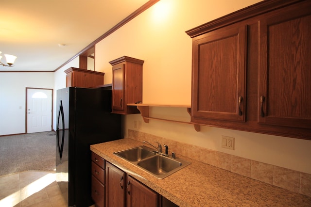 kitchen featuring light tile floors, a notable chandelier, ornamental molding, sink, and black fridge