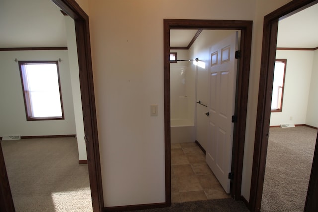 hall with ornamental molding and dark carpet