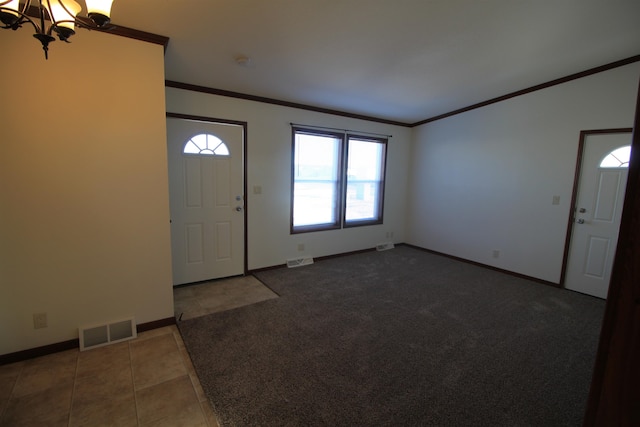 entrance foyer with dark tile flooring, a chandelier, crown molding, and a wealth of natural light