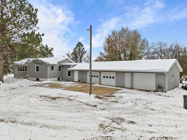 snow covered rear of property featuring a garage