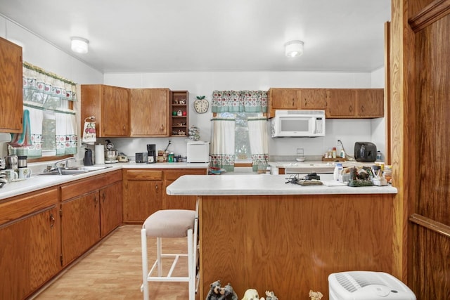 kitchen with a breakfast bar area, sink, and light hardwood / wood-style flooring