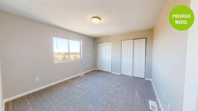 unfurnished bedroom with multiple closets and dark carpet