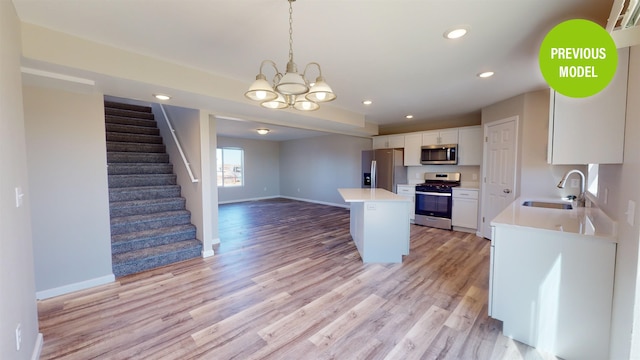 kitchen with appliances with stainless steel finishes, a notable chandelier, decorative light fixtures, white cabinetry, and light hardwood / wood-style flooring